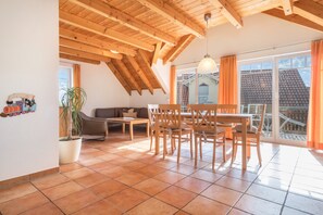 Un coin repas avec des meubles en bois, une plante en pot et une vue sur l’extérieur.