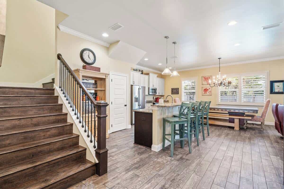 A spacious kitchen with a central island, wooden flooring, and a dining area with chairs.
