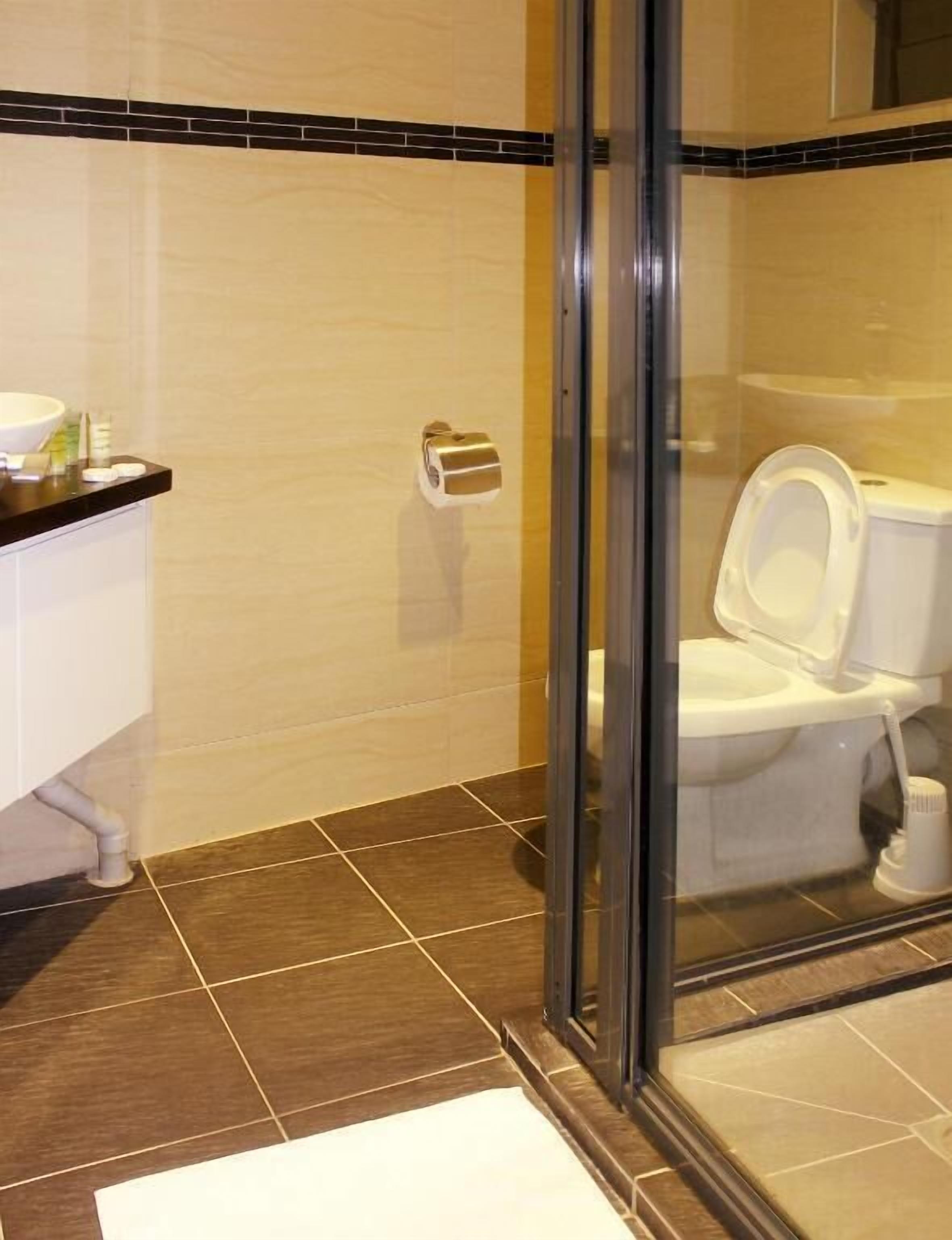 A bathroom with a toilet, sink, and glass shower enclosure.