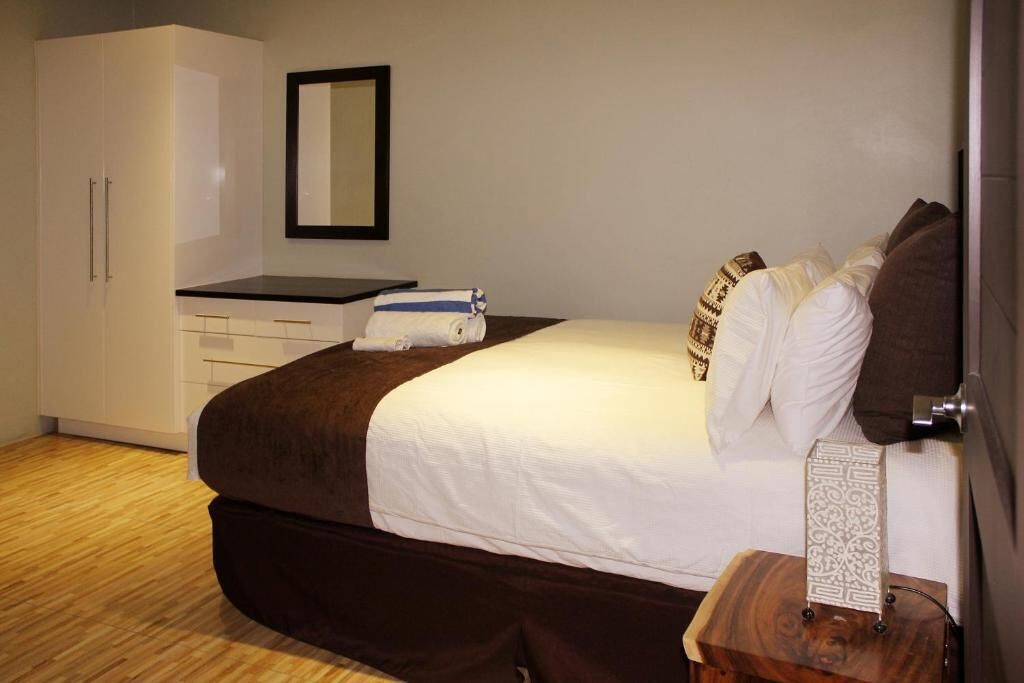 A bedroom with a large bed, a dresser, a mirror, and a bedside table with a decorative item.