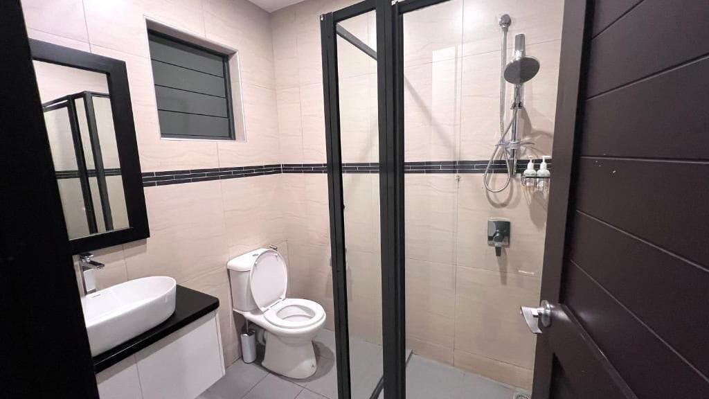 A bathroom with a toilet, sink, and shower area.