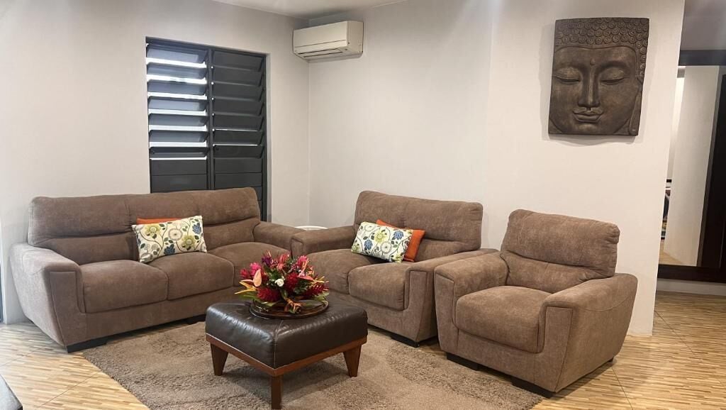 A living room with two sofas, a coffee table, and a Buddha statue on the wall.