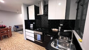 A modern kitchen with black and white cabinetry, a stainless steel sink, and a built-in oven.