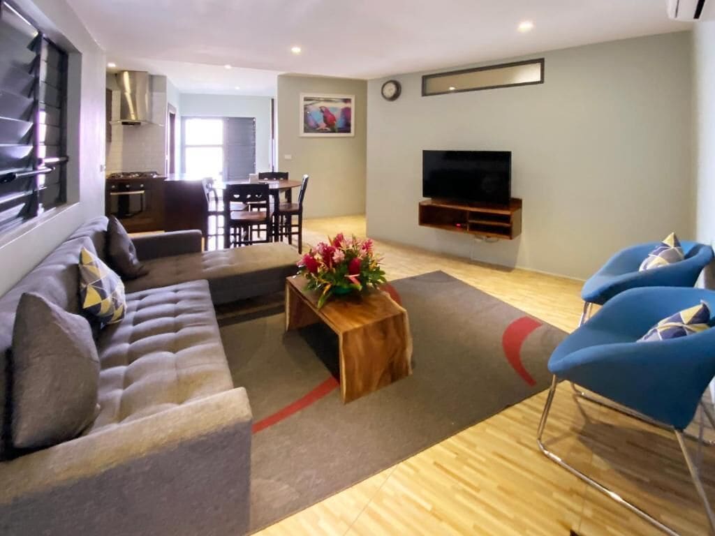 A modern living room with a sofa, coffee table, and blue chairs.