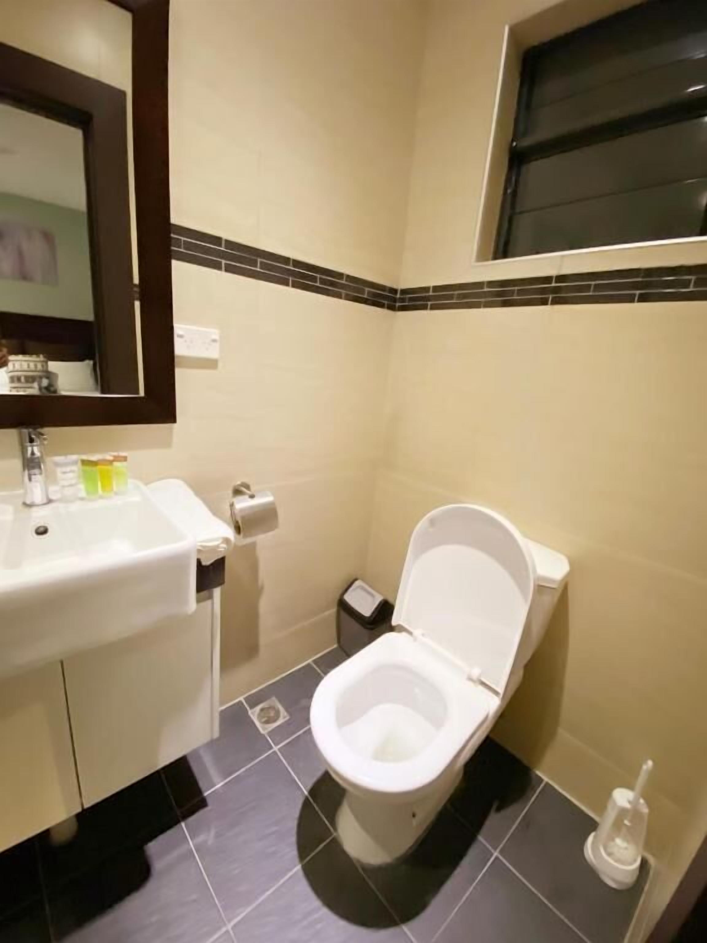 Un baño con lavamanos blanco, inodoro y un pequeño cubo de basura.