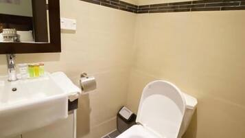 Un baño con lavamanos blanco, inodoro y un pequeño cubo de basura.