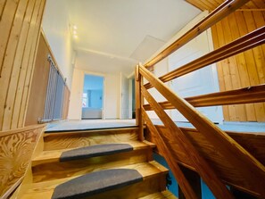 Una escalera de madera con barandilla que conduce a un piso superior.