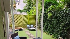 A patio with a table, chairs, and a small garden area with artificial grass and a wooden fence. - Apartment Bernstein - Ferienwohnung Bernstein Ruhig mit Garten (Rostock)