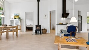 A modern living room with a central fireplace, a dining area, and a kitchen with stainless steel appliances. - "Majvor" - 200m from the sea by Interhome (Hadsund)