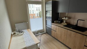 A compact kitchen with a dining table, chairs, and a window with a view of buildings.