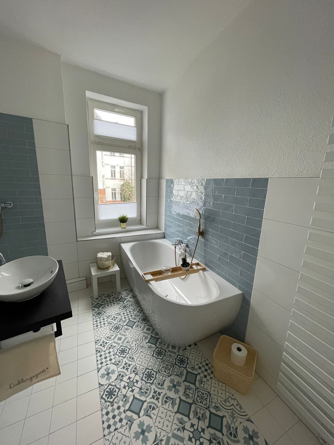 A modern bathroom with a freestanding bathtub, a vanity with a sink, and a patterned floor.