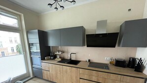 A modern kitchen with a central island, dark cabinetry, and a window providing natural light.
