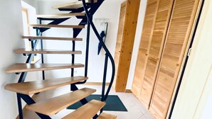Una escalera de caracol con escalones de madera y barandillas de metal negro, que conduce a un segundo piso.