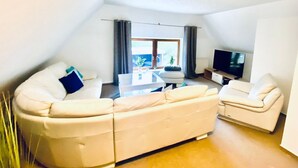 Una sala de estar moderna con un conjunto de sofá, un televisor de pantalla plana y un comedor con mesa y sillas.