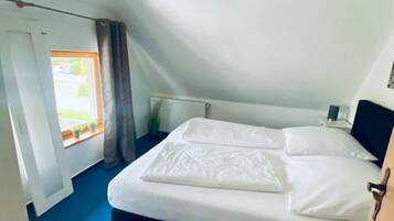 Ein Schlafzimmer mit Bett, einem Vorhangfenster, einem Deckenventilator und Blick ins Freie.