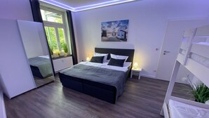 Ein modernes Schlafzimmer mit einem großen Bett, Nachttischen, einem Fenster mit Vorhängen, einem Gemälde an der Wand und einer Tür.