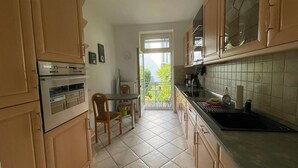 Eine kleine Küche mit Essbereich, Blick ins Freie und einem großen Fenster.