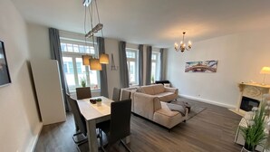 Ein modernes Wohnzimmer mit Essbereich, einer Couch, einem Kamin und einer Chandelier.