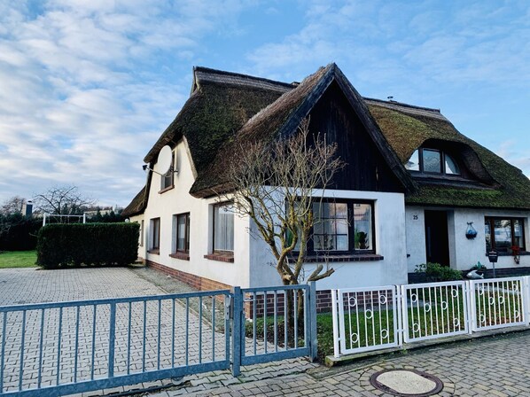 A traditional house with a steeply pitched roof, a visible chimney, and a gated driveway.