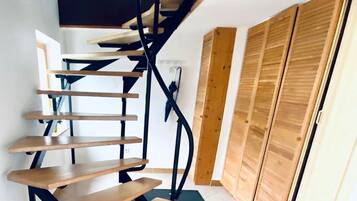 Eine Wendeltreppe mit Holzstufen und schwarzen Metallgeländern, die zu einer zweiten Etage führt.