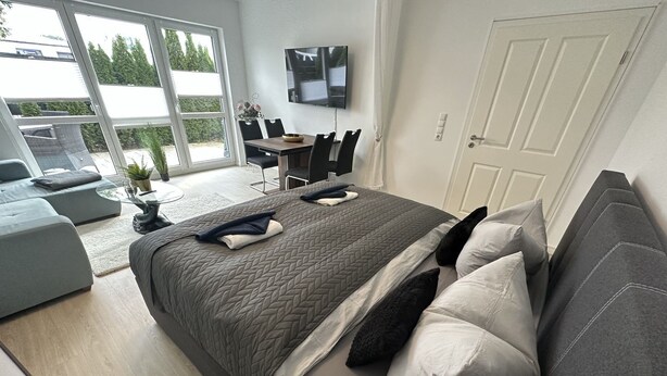 Una camera da letto moderna con un letto grande, un divano, un tavolo da pranzo e una televisione.