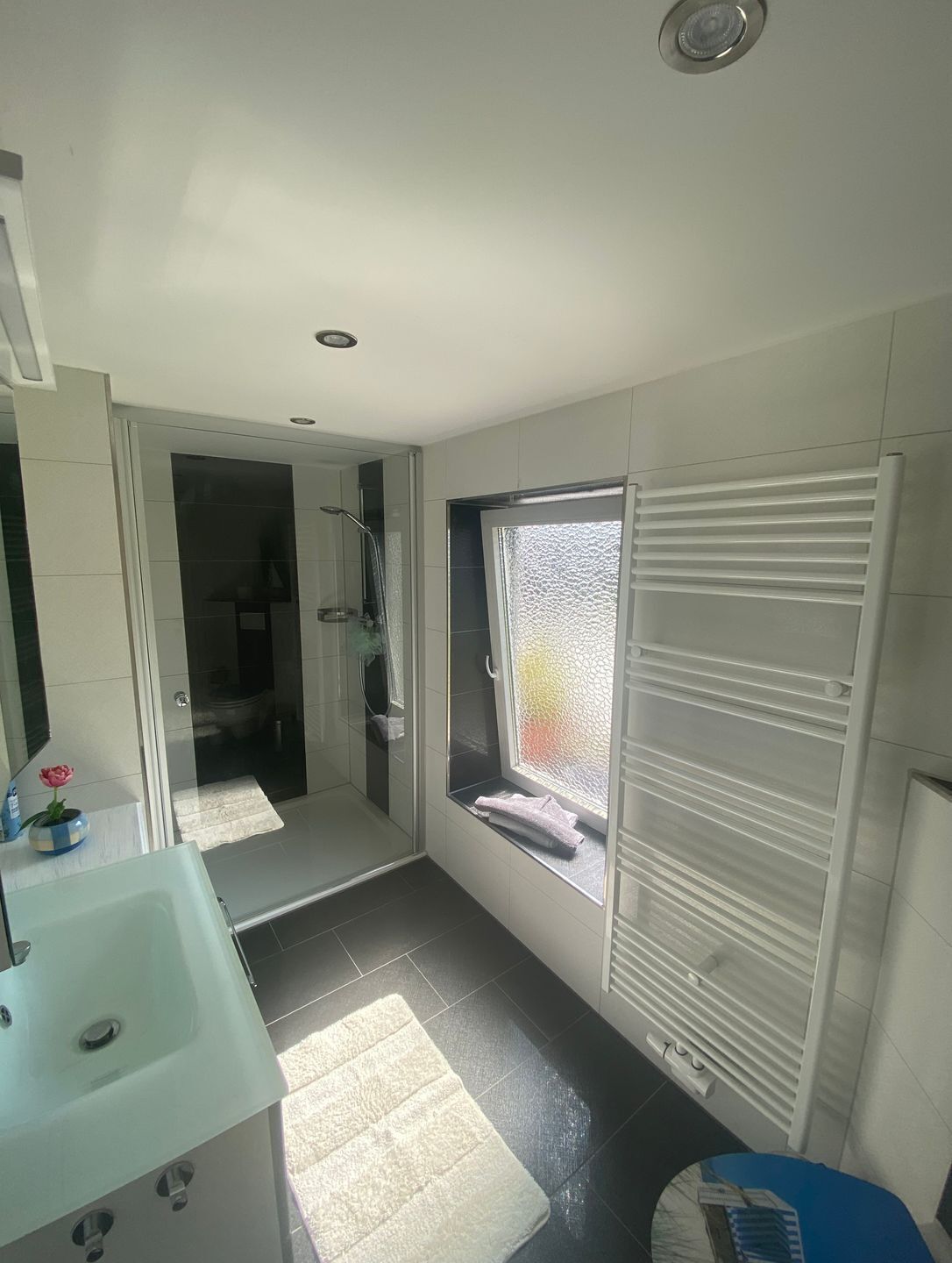 Un bagno moderno con doccia, lavandino e finestra con persiane.