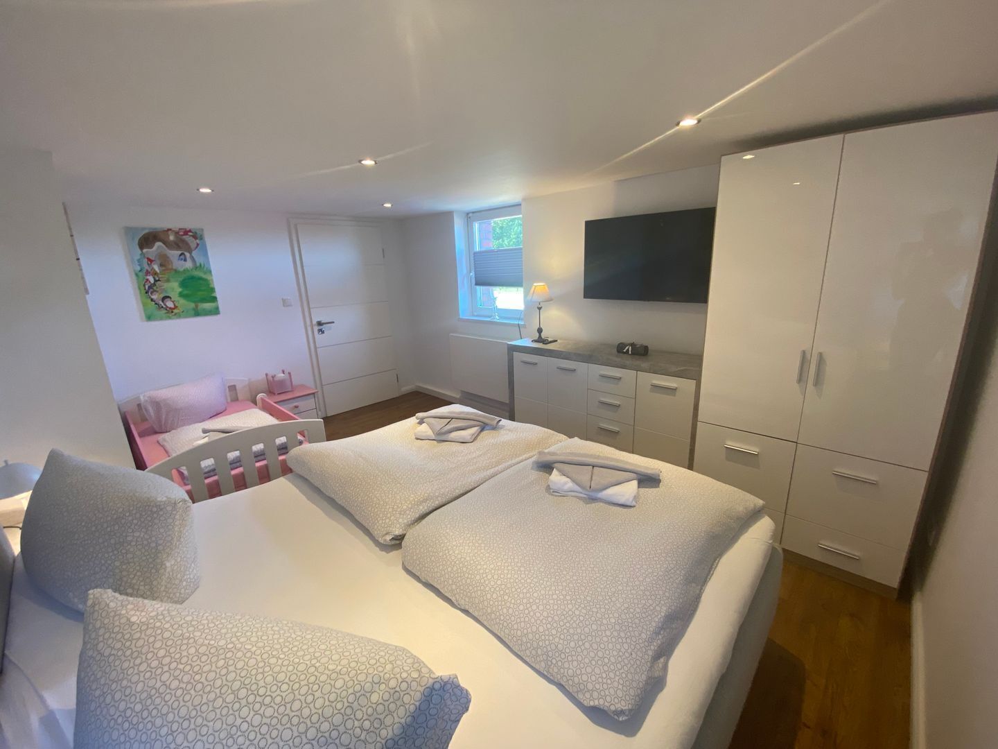 A bedroom with a bed, a desk, a chair, a wardrobe, and a TV.