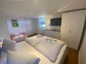 A bedroom with a bed, a desk, a chair, a wardrobe, and a TV.