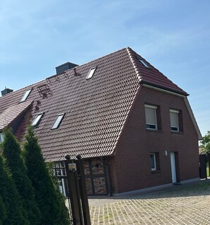 A two-story house with a sloped roof, a brick exterior, and a paved driveway.