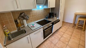 Une cuisine de taille réduite, équipée d’une cuisinière, d’un évier et d’un petit coin repas.
