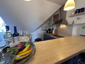 A modern kitchen with a wooden countertop, wine bottles, glasses, and a fruit bowl. - Ostseeanker Ferienhaus mit Großem Garten, kl. Eigener Fußballplatz, Smart-tv, Grill - Ostsee-anker (Zingst)