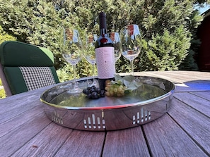 Une bouteille de vin posée sur une table en verre, avec deux verres à vin et des raisins.