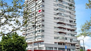 Un immeuble à plusieurs étages, doté de balcons, de grandes fenêtres et d’un toit plat.