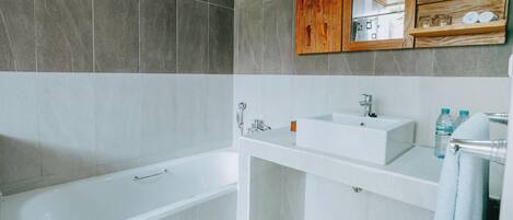 A modern bathroom with a bathtub, a sink, and a mirror.