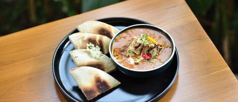 A plate with a bowl of soup and three pieces of flatbread on a wooden table.