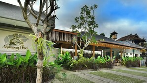 A building with a sign reading "Mahayoga Ubud" and a covered outdoor seating area with plants. - Mahayoga Ubud Private Pool Villa Spa And Resto (Ubud)