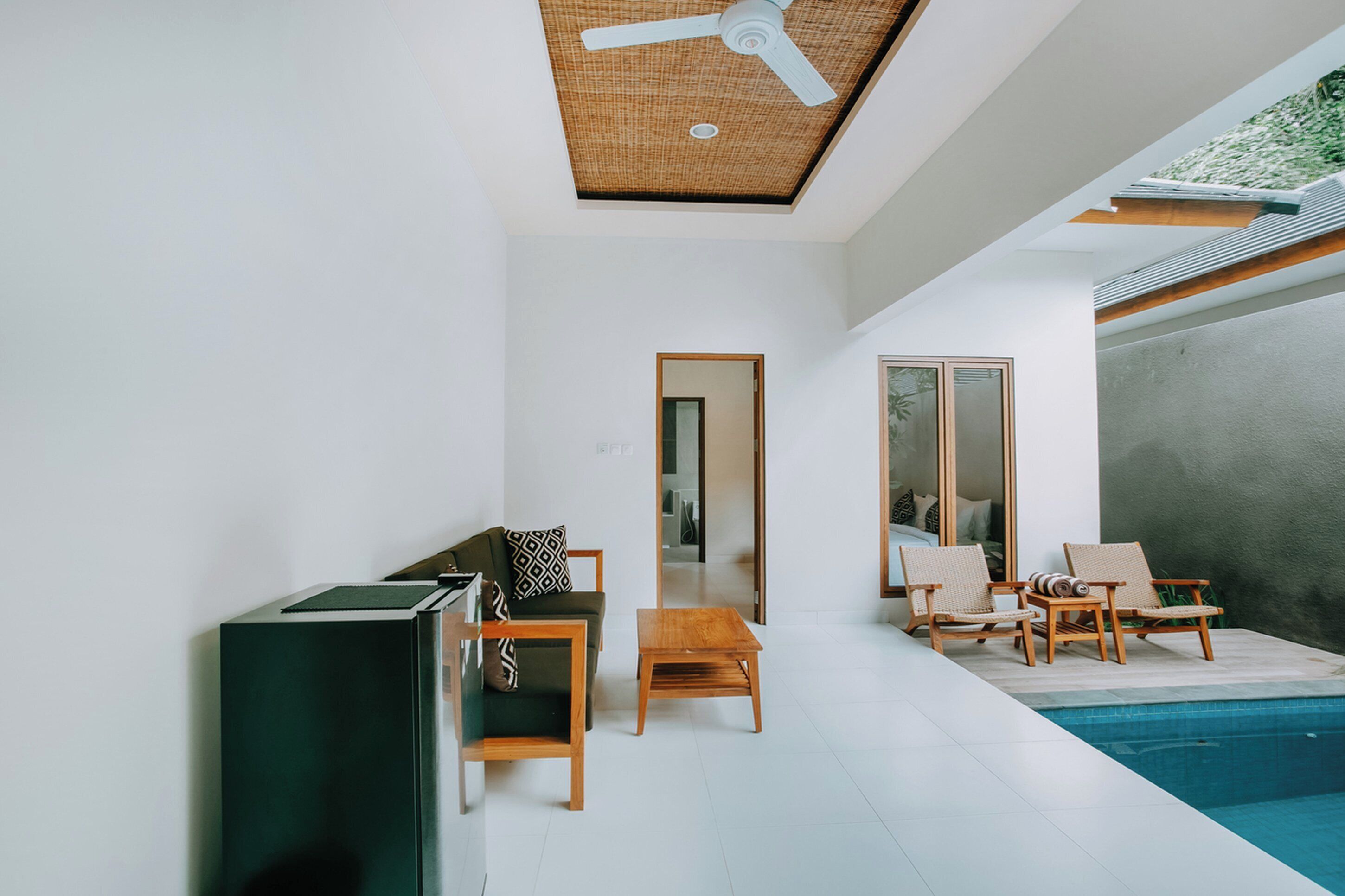 Uma sala de estar moderna com piscina, ventilador de teto e mesa de centro de madeira.