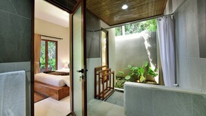 A modern bathroom with a shower, a wooden bed, and a view of greenery outside. - Mahayoga Ubud Private Pool Villa Spa And Resto (Ubud)