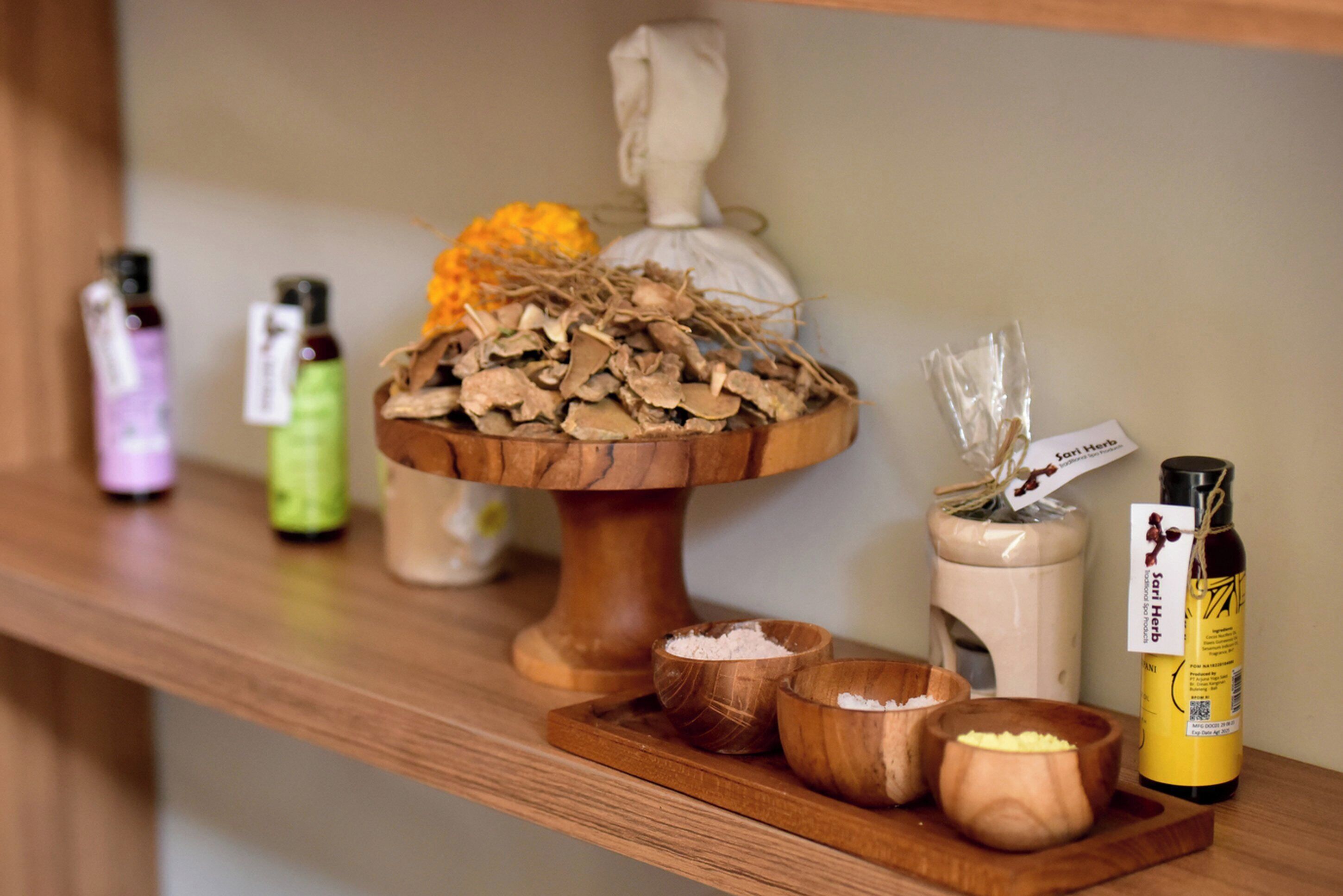 A wooden shelf with various items including bottles, bowls, and a decorative ceramic piece.