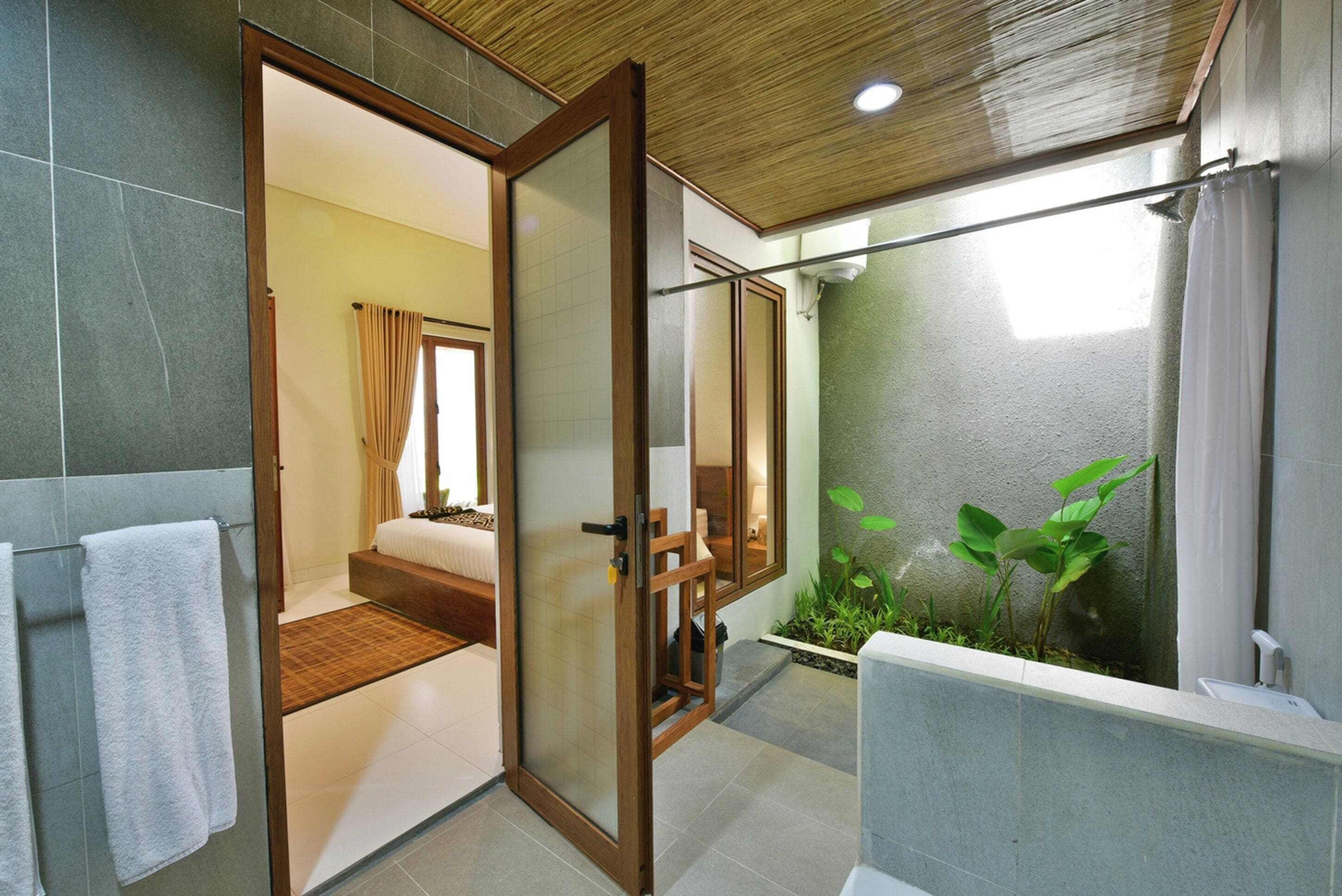 A modern bathroom with a glass shower enclosure, a visible toilet, and a small plant area.