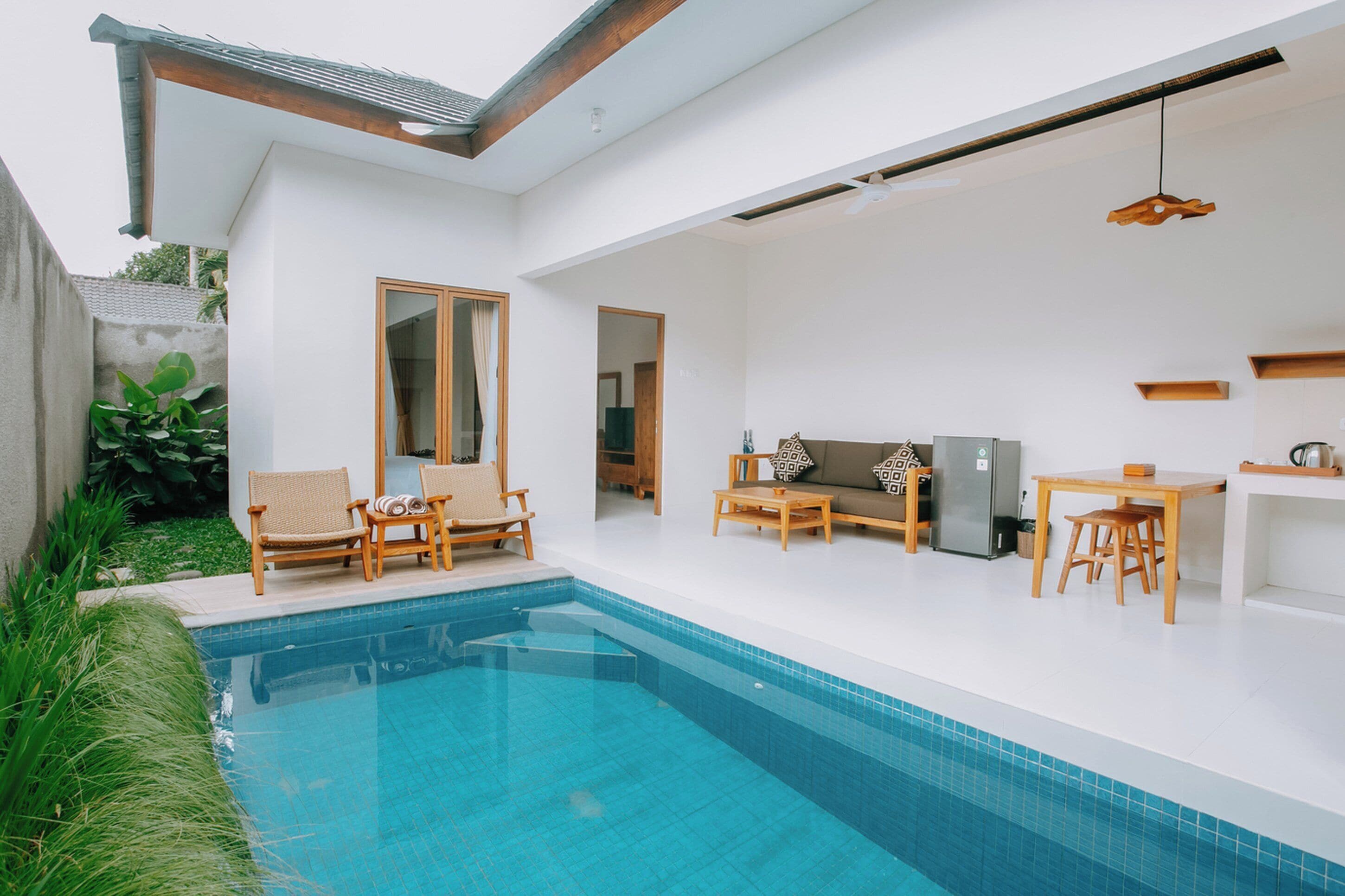 Una casa moderna con piscina, muebles de madera y una zona de cocina.