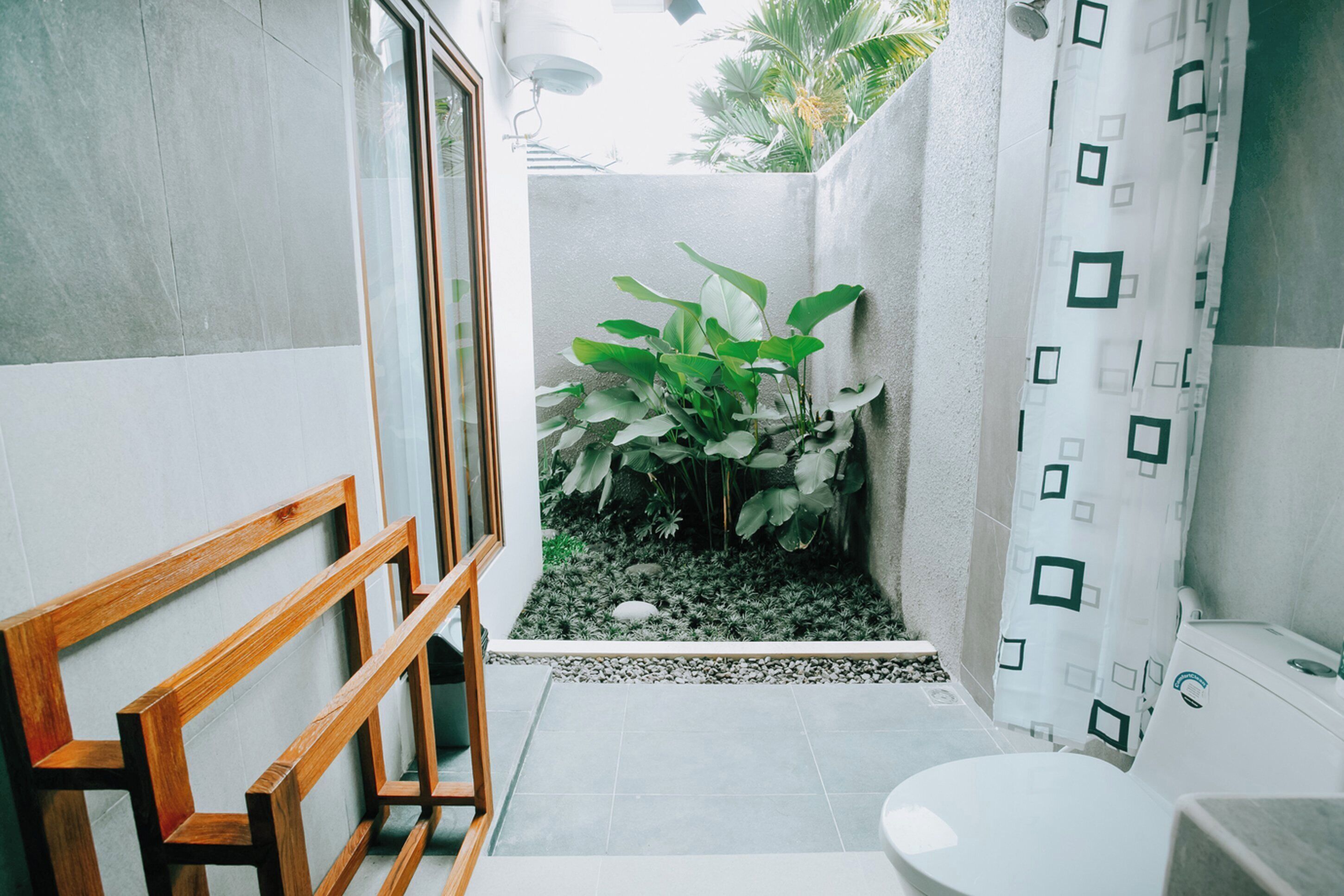 A bathroom with a toilet, a sink, a shower, and a small garden area with plants.