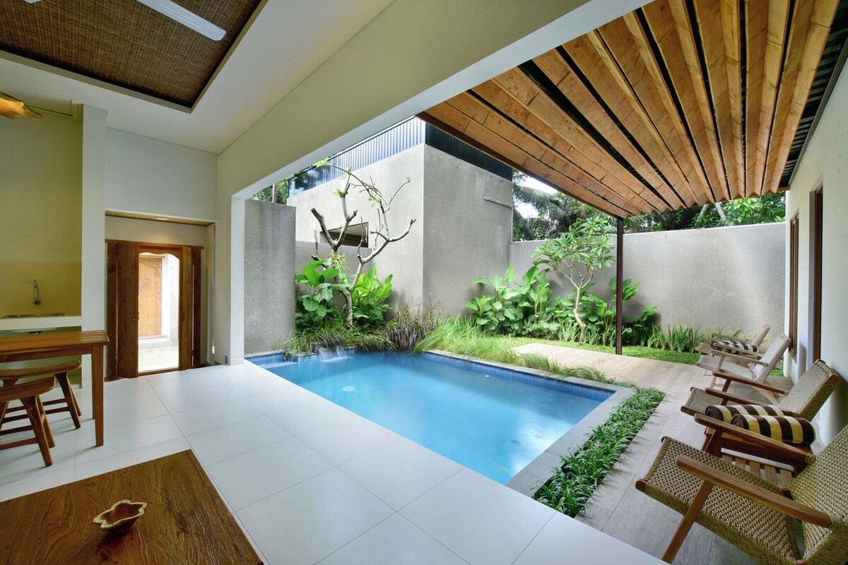A modern indoor pool area with a clear view of the surrounding greenery and a wooden ceiling.