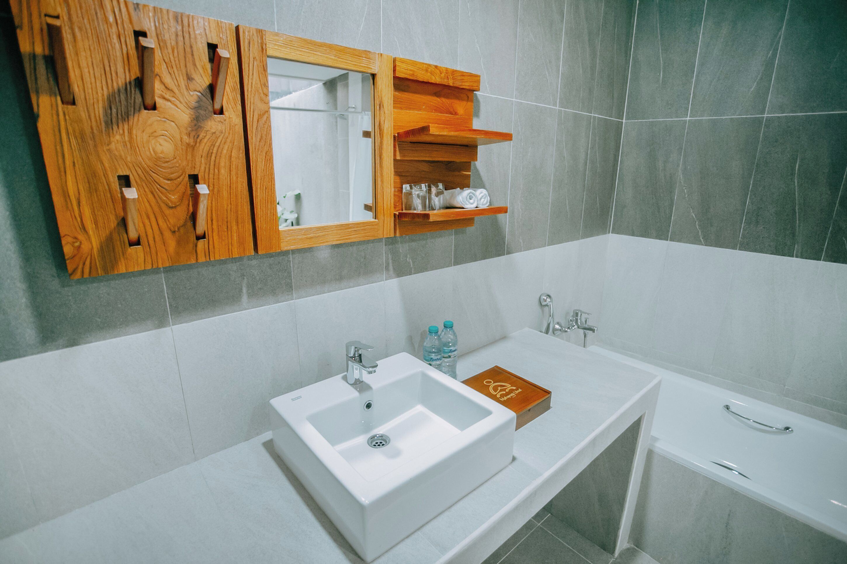 Une salle de bain moderne avec un lavabo blanc, un meuble-lavabo en bois et un miroir.
