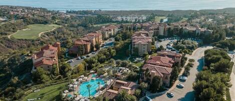 Vista aérea de un complejo turístico con villas, piscina y campo de golf.