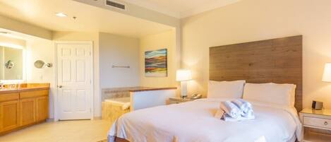 A hotel room with a bed, bedside tables, a bathroom, and a wooden headboard.