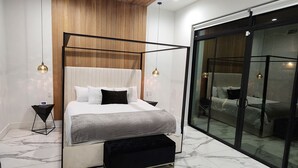 Een moderne slaapkamer met een hemelbed, een plafondventilator en een grote schuifglazen deur naar een balkon.