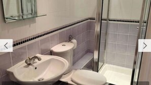 Casa de banho com lavatório, sanita e cabine de duche em vidro.
