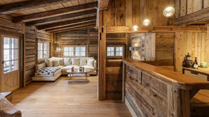 Interior de una cabaña de troncos con una sala de estar acogedora, que incluye un sofá y una mesa de centro.