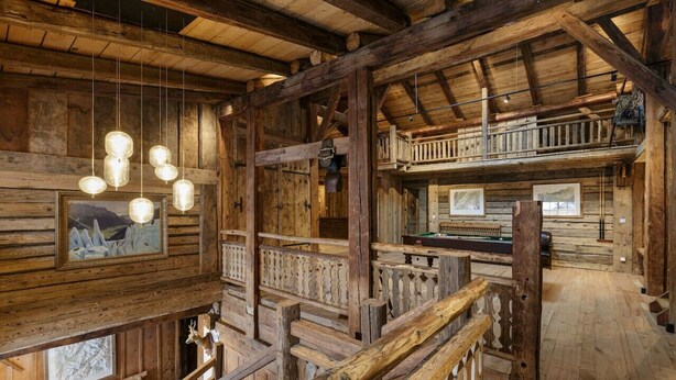 Un interior rústico de madera con balcón, barandillas de madera y lámparas colgantes.
